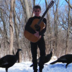 Steve Tibbetts holding guitar among geese