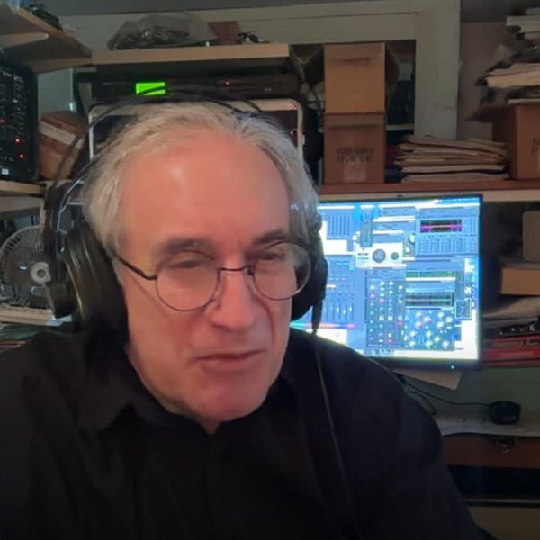 Larry Fast of Synergy wearing headphones with computer screen and electronics in background
